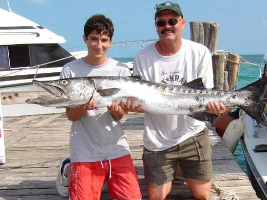 Anglers holding a barracuda caught while fishing in Cancun