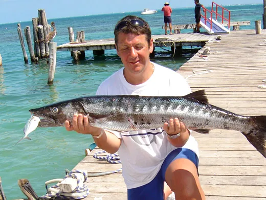 Angler holding a barracuda caught while fishing in Cancun