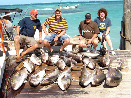 A smiling charter guest holding a heavy Greater Amberjack reeled up from a deep winter wreck network