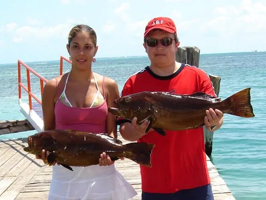Anglers holding grouper caught while fishing in Cancun