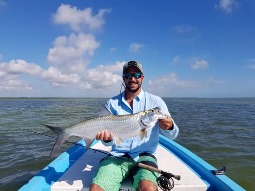 Angler holding a tarpon caught while fishing in the Cancun Lagoon