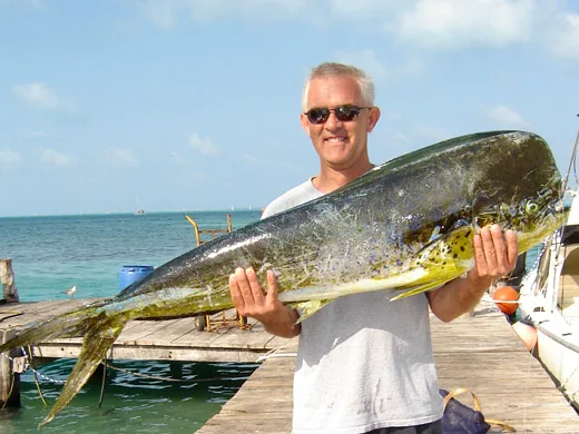 An offshore sportfishing angler proudly showcasing a massive, brightly colored golden Mahi Mahi caught in Cancun