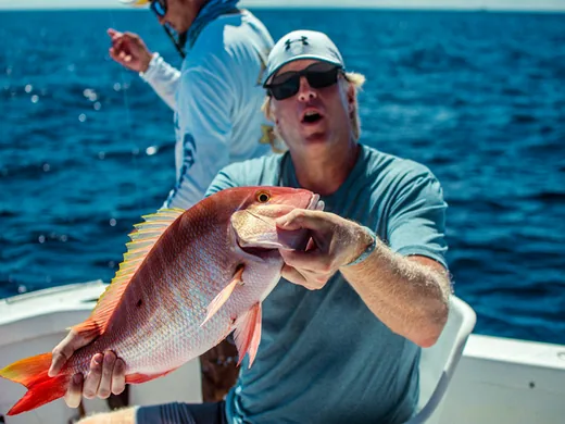 Angler holding a snapper caught while bottom fishing in Cancun